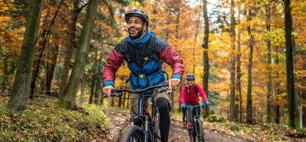 Mann und Frau fahren mit ihrem Mountainbike durch den Wald